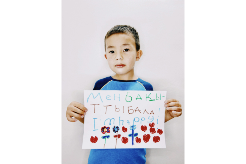 enfant tenant une pancarte avec un message joyeux